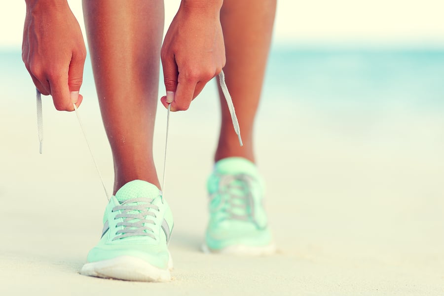 Woman tying her running shoe laces, preparing to go for a run.